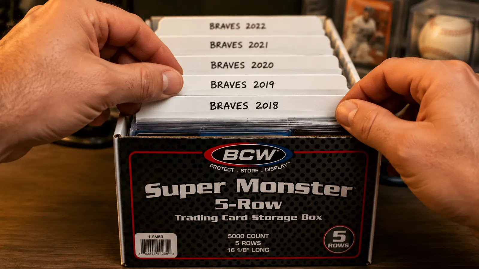 Close-up of labeled card dividers inside a BCW storage box, showing team and year tabs for a baseball card collection