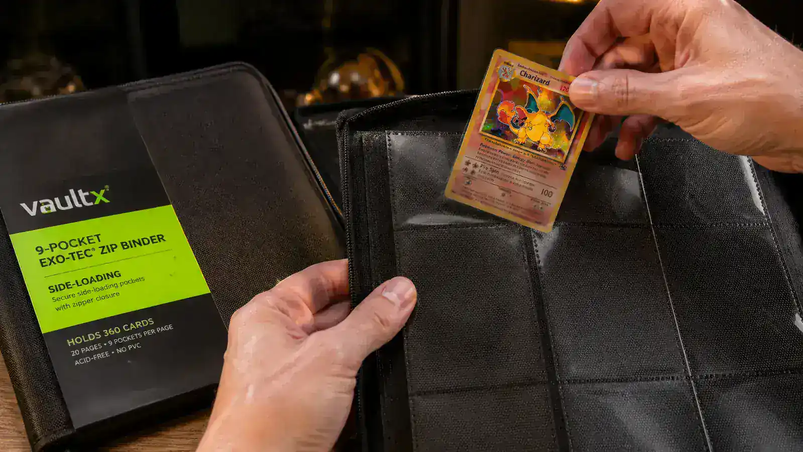 Hand sliding a Pokemon card into a side-loading 9-pocket binder page in the Vault X Exo-Tec binder